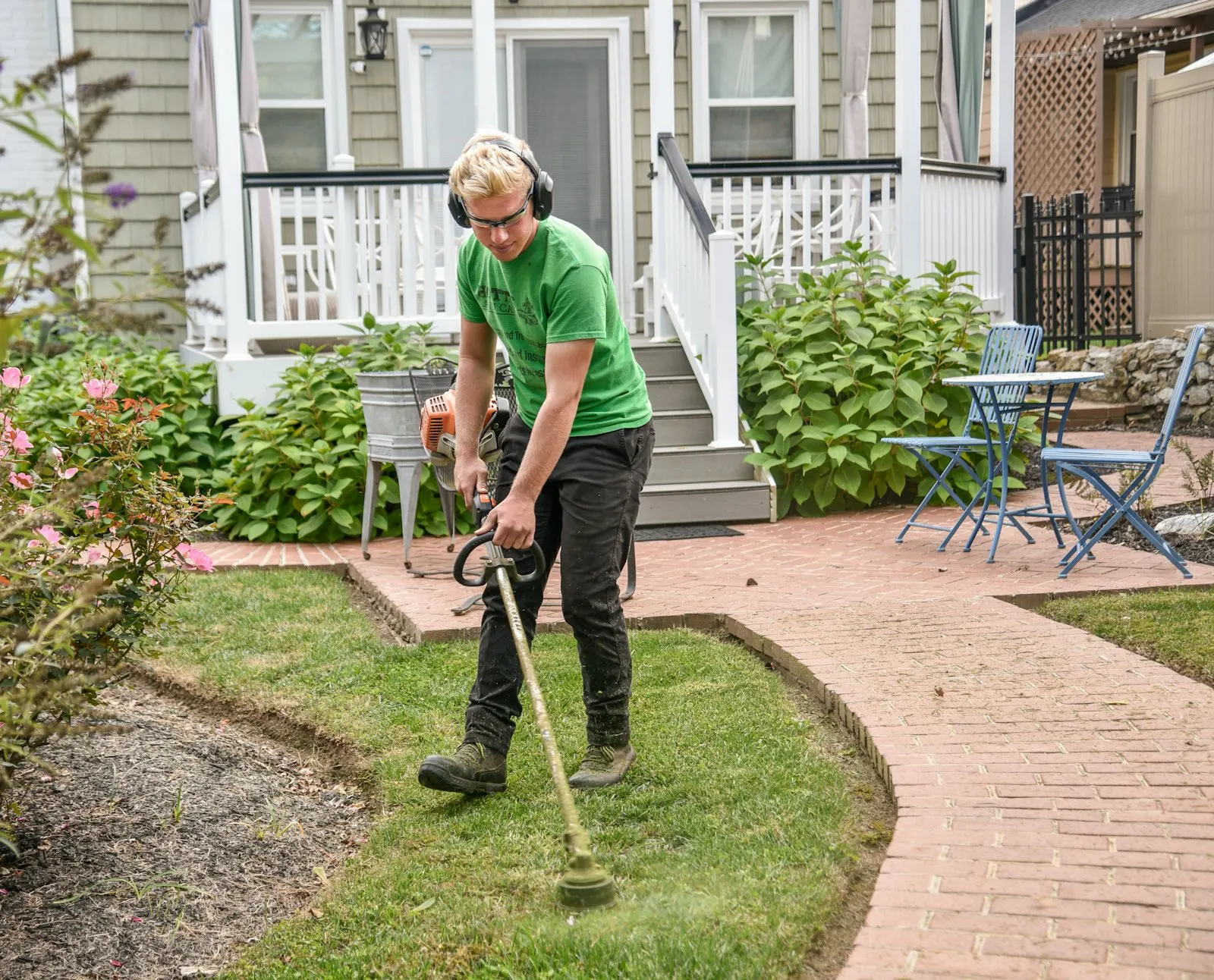 String trimmer edging the gravel-to-sidewalk border on a Phoenix residential street.